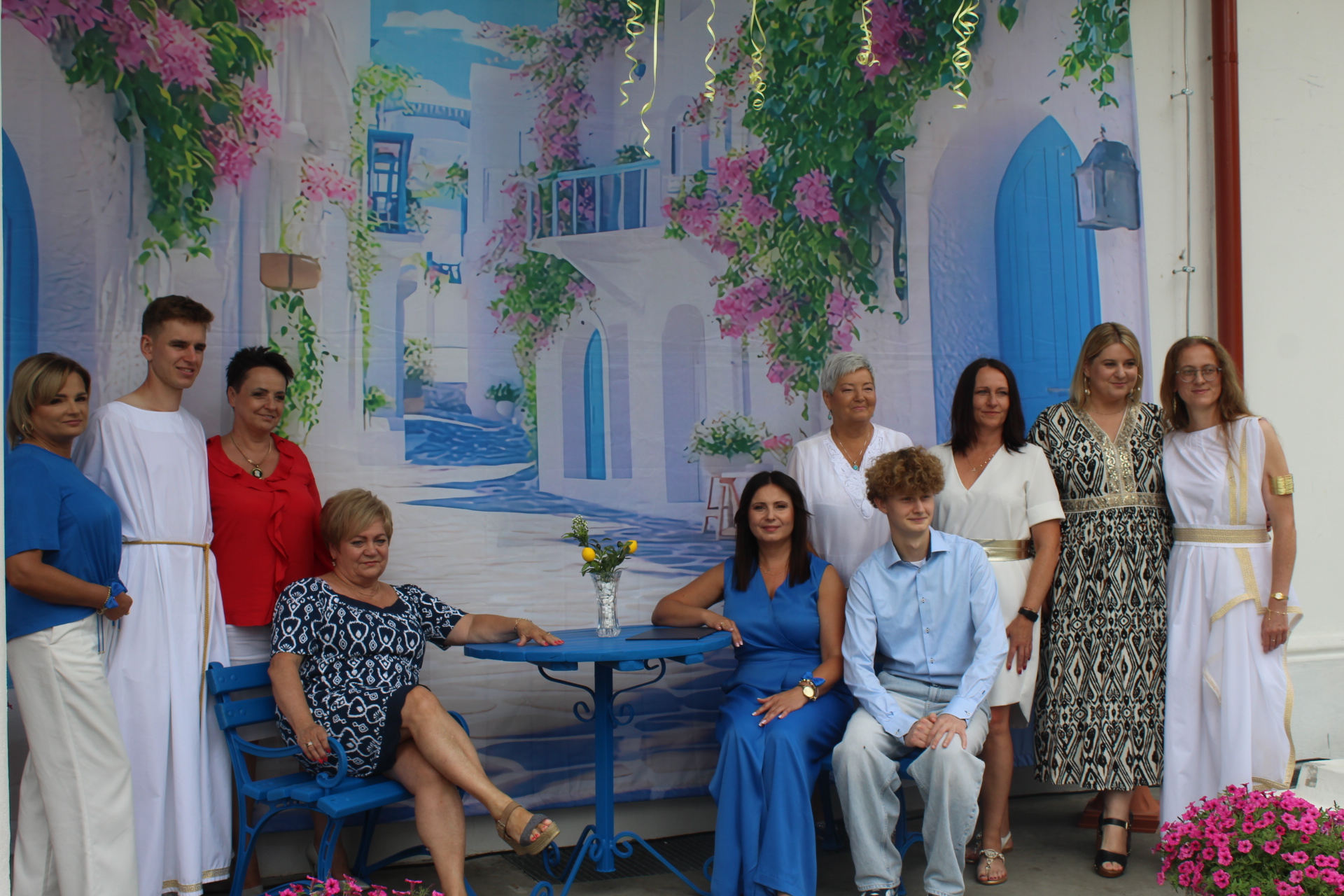 Goście na wspólnym zdjęciu z artystami, w tle krajobraz greckiego ogrodu