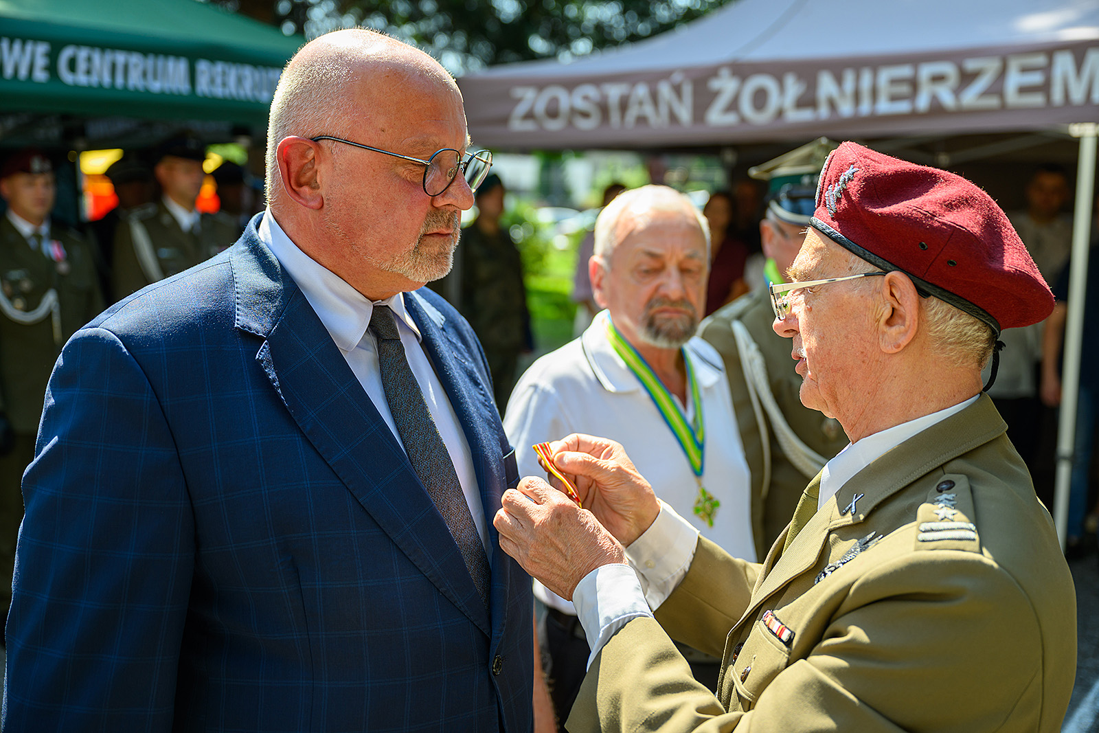 Przedstawiciel kombatantów wiesza medal u marynarki starosty